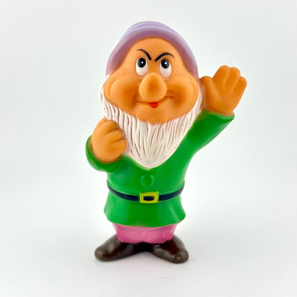 Toy figure of a character with a green outfit and purple hat on a white background