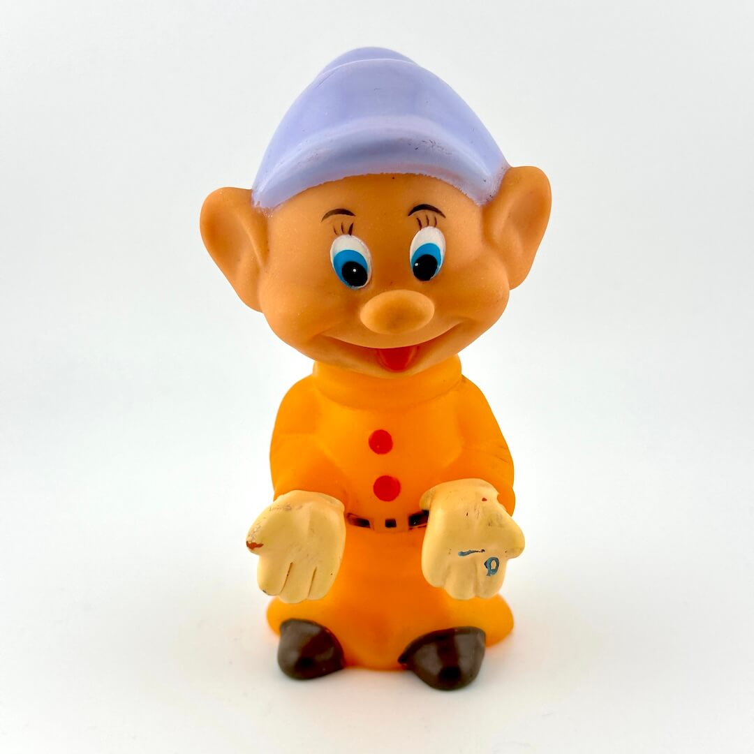 Cartoon character figurine with orange outfit and purple hat on a white background