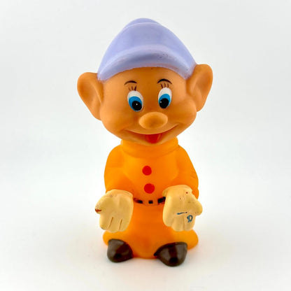 Cartoon character figurine with orange outfit and purple hat on a white background