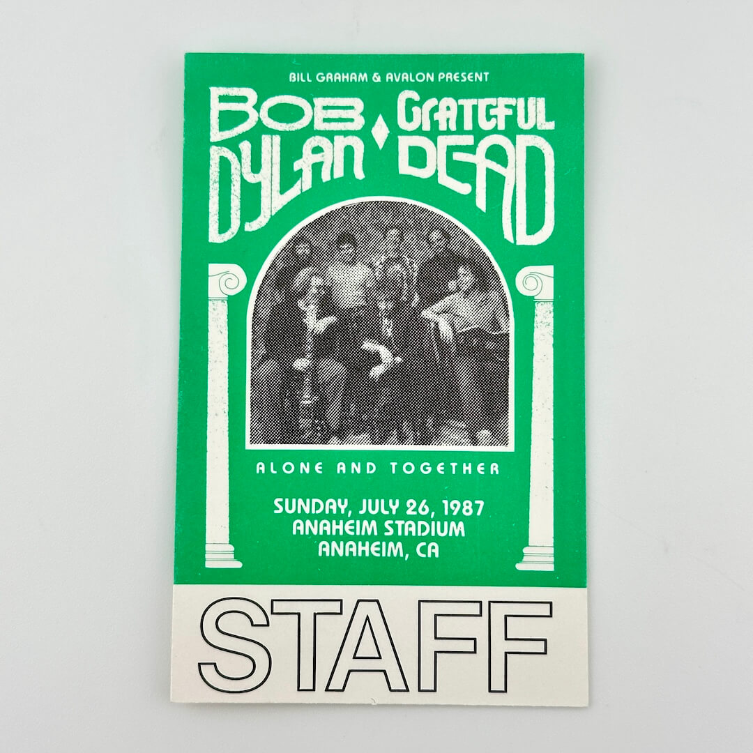 Green staff backstage pass with white text with event details surrounding black and white image of artists. 