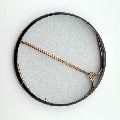 Round metallic object with a copper-colored rod on a white background