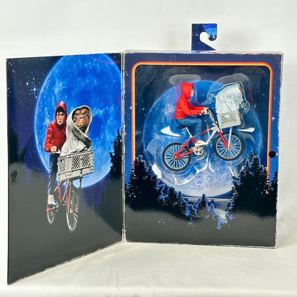 Toy figure of a person on a bike with a dog in a basket against a moonlit sky background