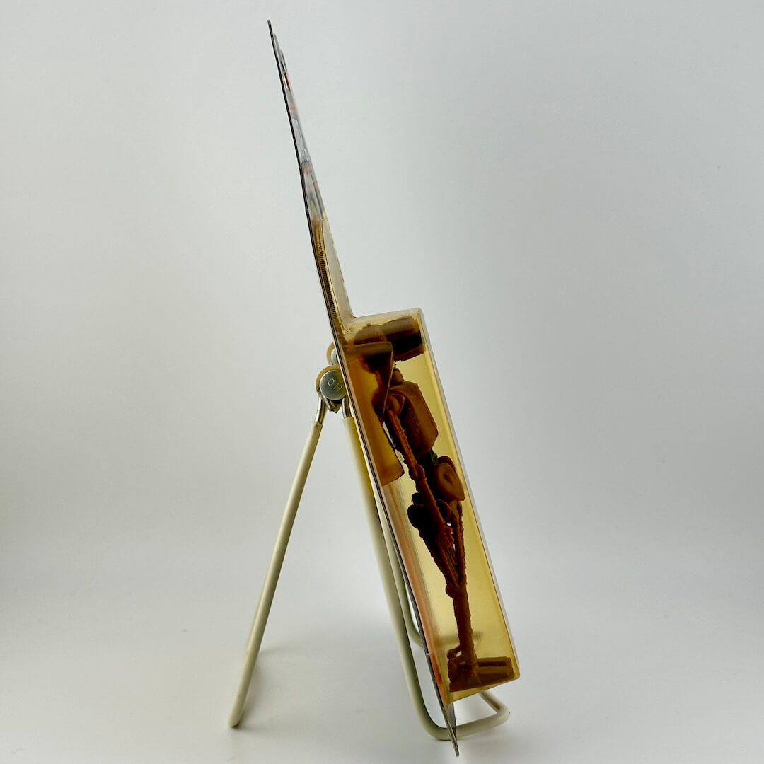 Side view of Star Wars action figure still in packaging on easel on white background. 
