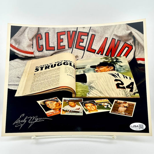 Photo of baseball memorabilia featuring a Cleveland player, open book, and trading cards on a white background