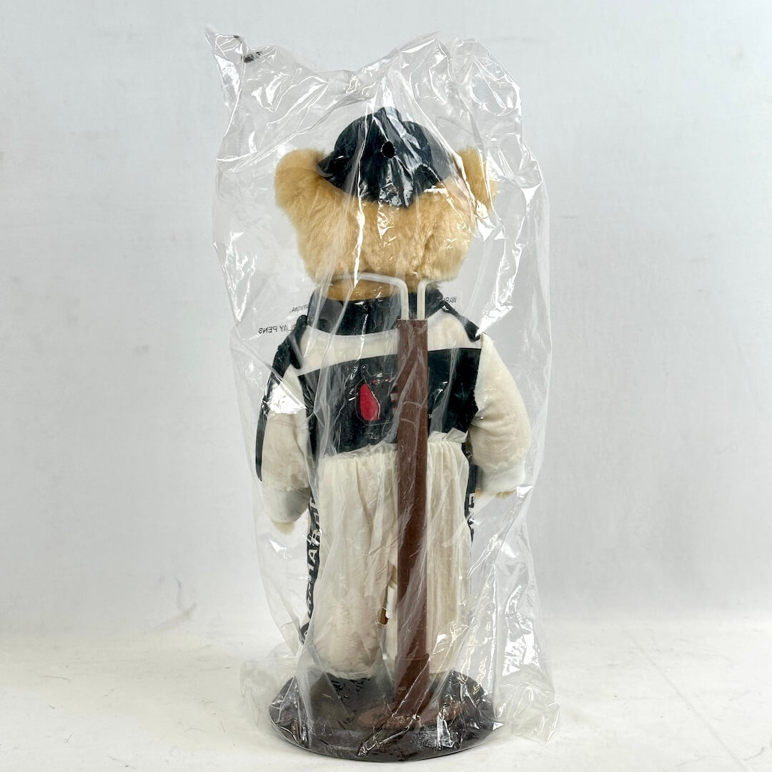 Plush toy bear in a racing uniform, wrapped in clear plastic on a white background