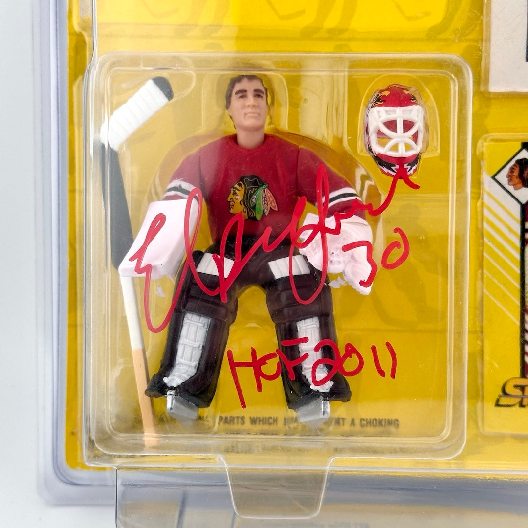 Plastic action figure in Redskins jersey holding hockey stick with red marker signature across front, Ed Belfour HOF 2011