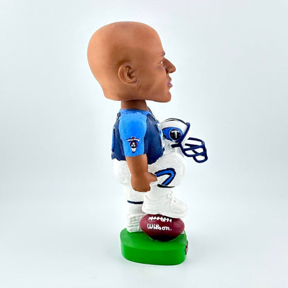 Bobblehead of football player holding helmet against white background. 