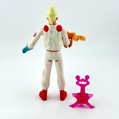 Toy figure in a space suit with a weapon, standing next to a pink object on a white background