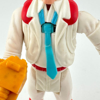 Toy figure with a white coat, red vest, and blue tie on a light gray background