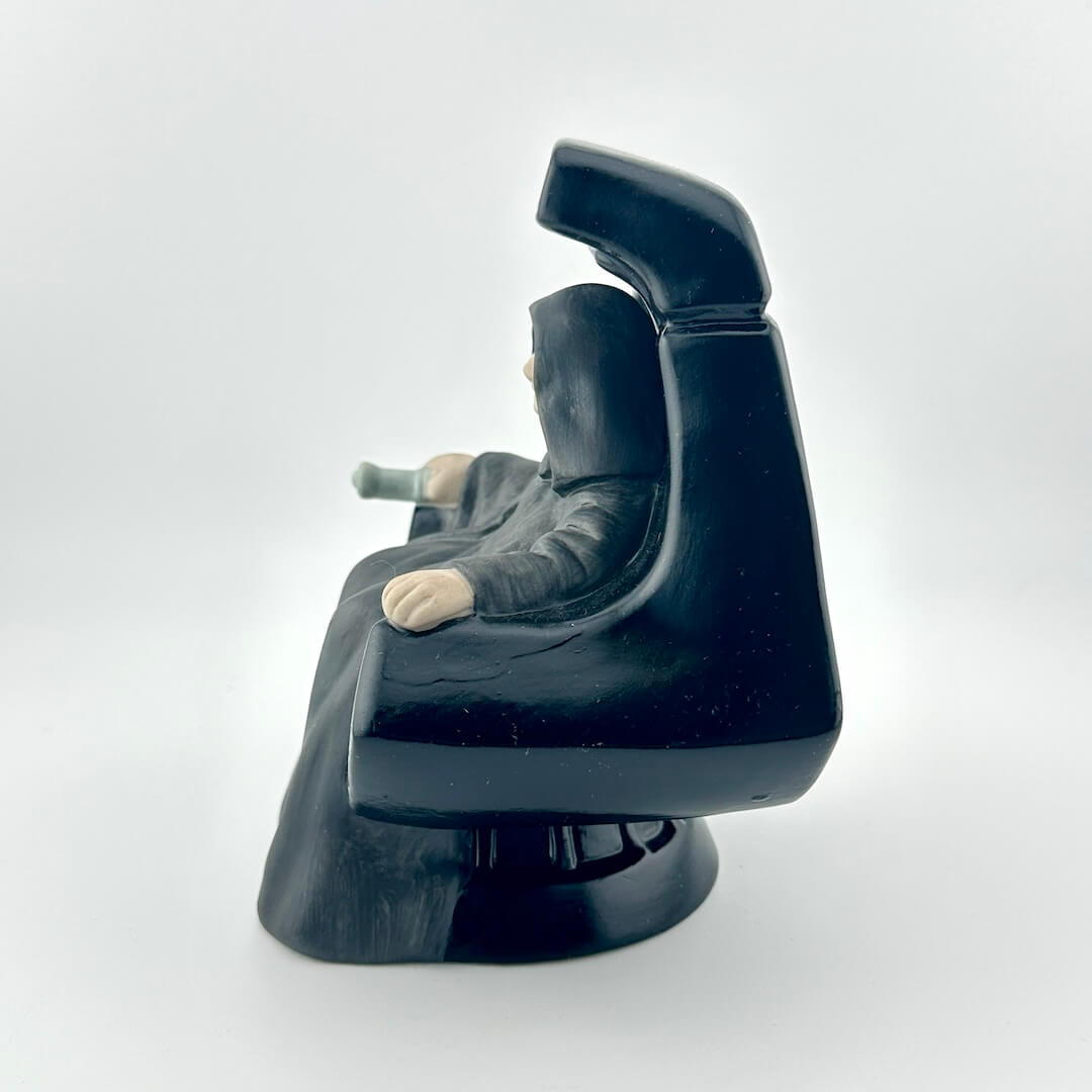 Ceramic figurine of the Star Wars Emperor in throne against white background. 