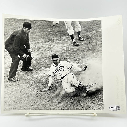 Vintage black and white photograph of a baseball player sliding into home plate with an umpire and another player in the background.