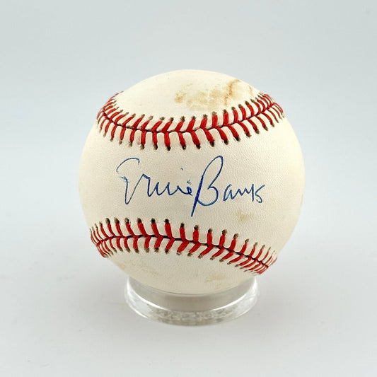 Baseball with autograph in sweet spot on clear stand against white background. 