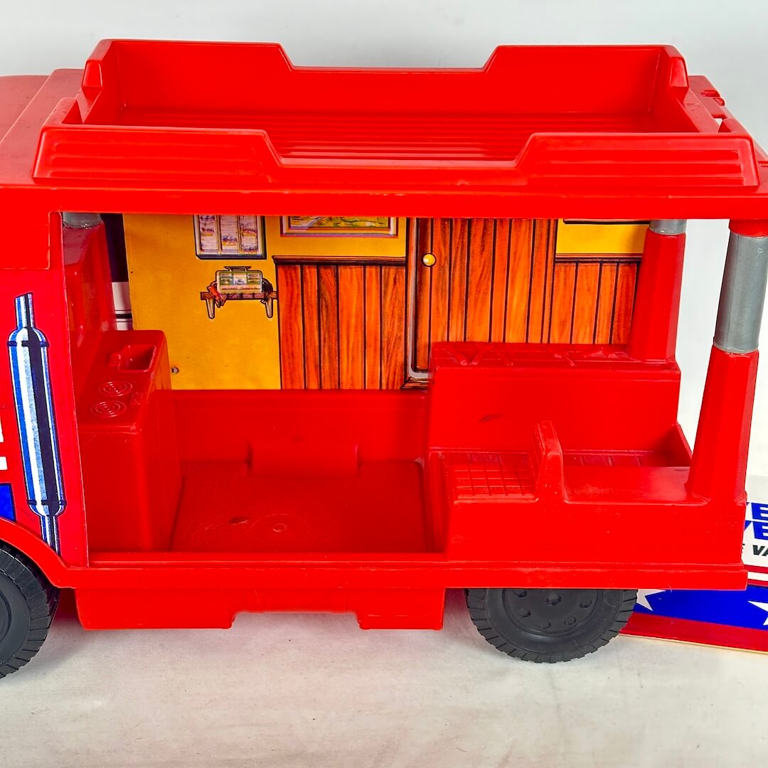 Red toy truck with a small model room inside on a white background