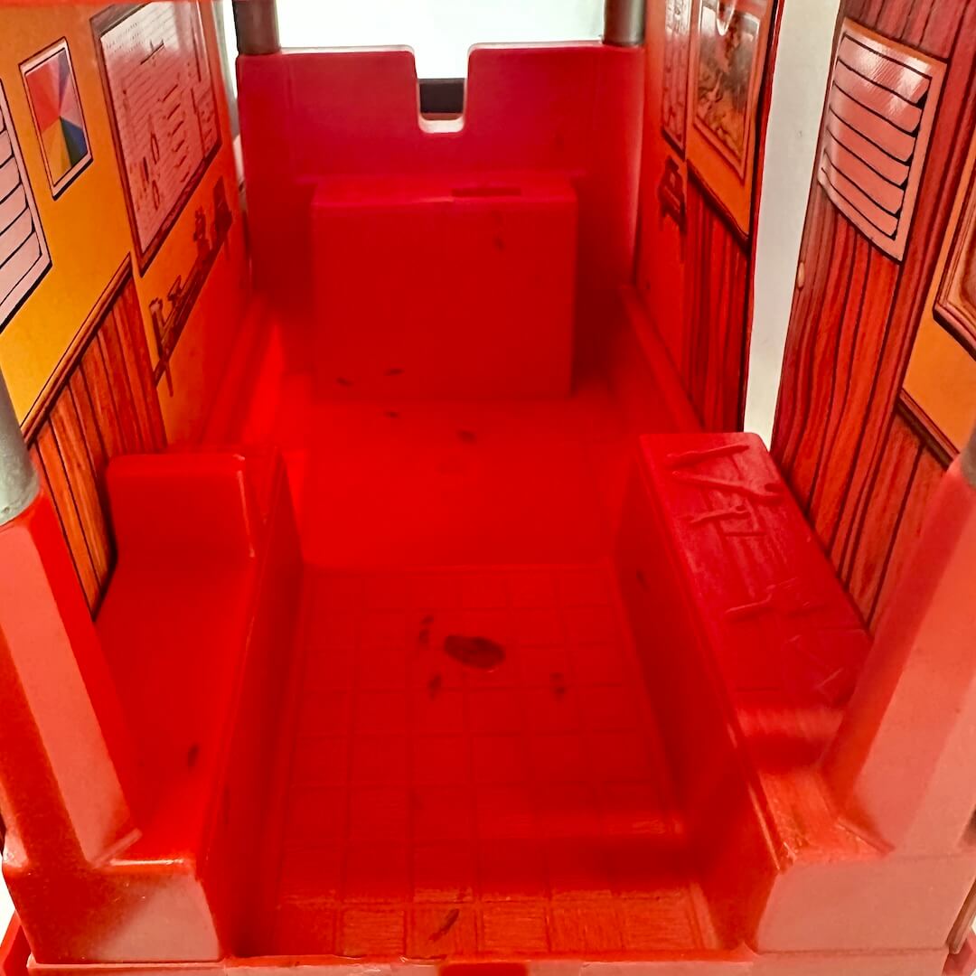 Red plastic play structure with steps inside a building