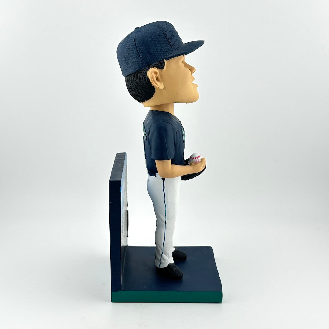 Bobblehead of a baseball player in a blue uniform with a cap, holding a ball, on a white background.