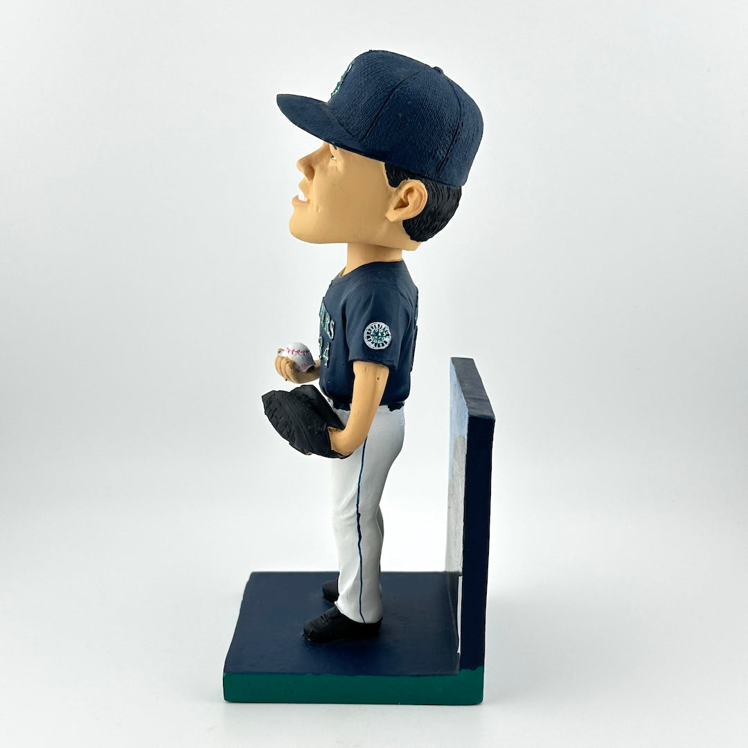 Bobblehead of a baseball player in a navy uniform with a white base on a light gray background