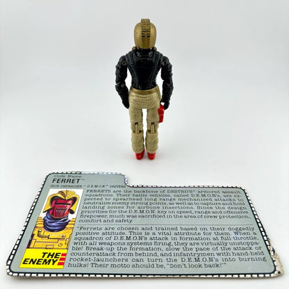 Toy figure of a character in a black suit with a card about 'The Enemy' on a white background