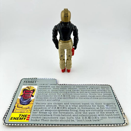 Toy figure of a character in a black suit with a card about 'The Enemy' on a white background