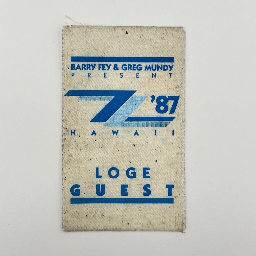 White fabric event pass with blue print with event info. Center has two interlocked Z's, both blue, one light blue.