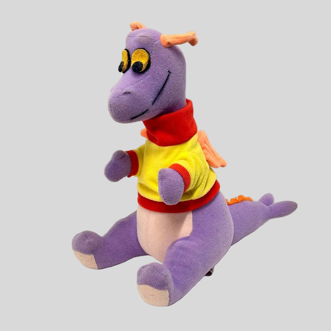Purple dragon plush toy with a colorful shirt on a white background