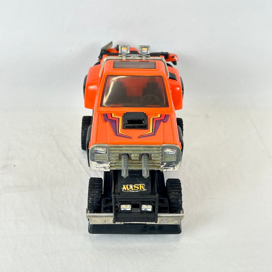 An orange toy truck with purple graphic decals, a black front bumper, and a silver grille.