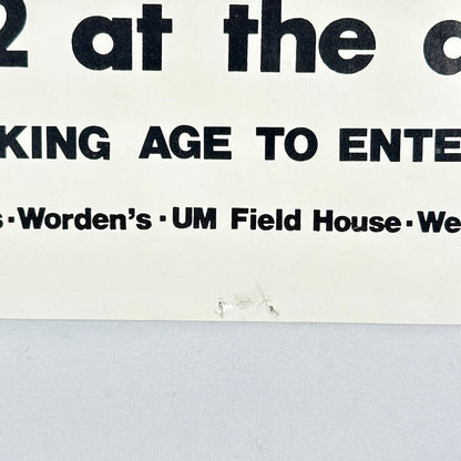Bottom center of poster with pin holes. 