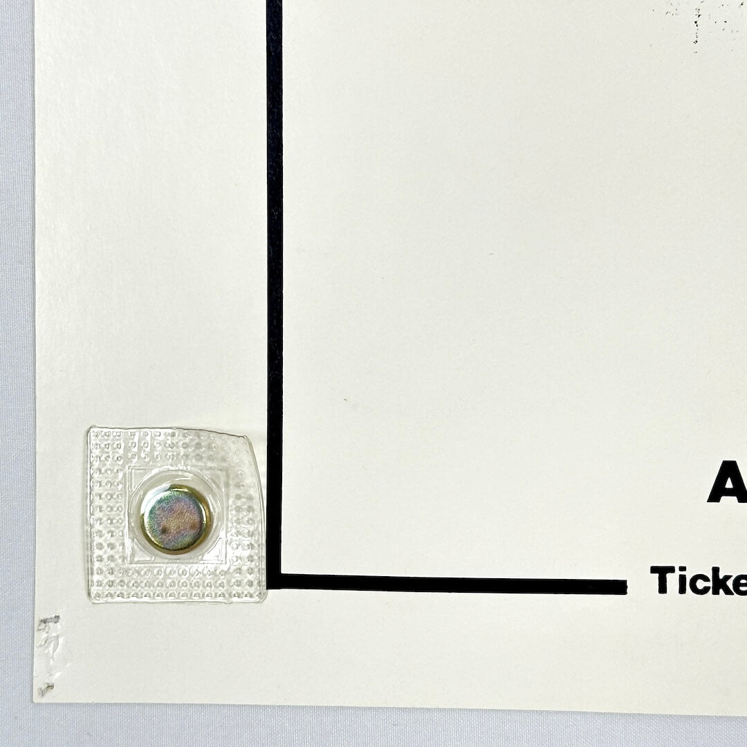 Bottom left corner of poster with pin holes. 