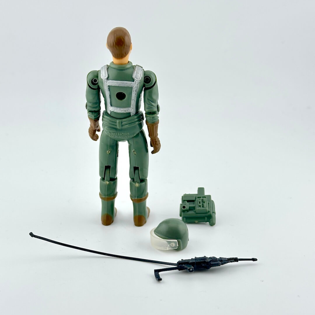 Toy figure in green space suit with helmet and antenna on a light gray background