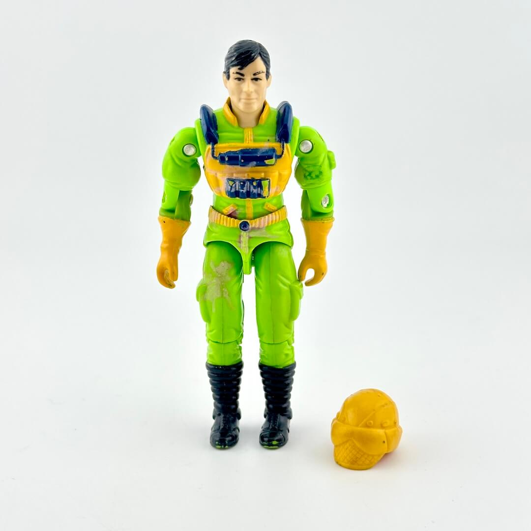 GI Joe action figure in green flight suit with yellow accents and yellow helmet, photographed on white background. 