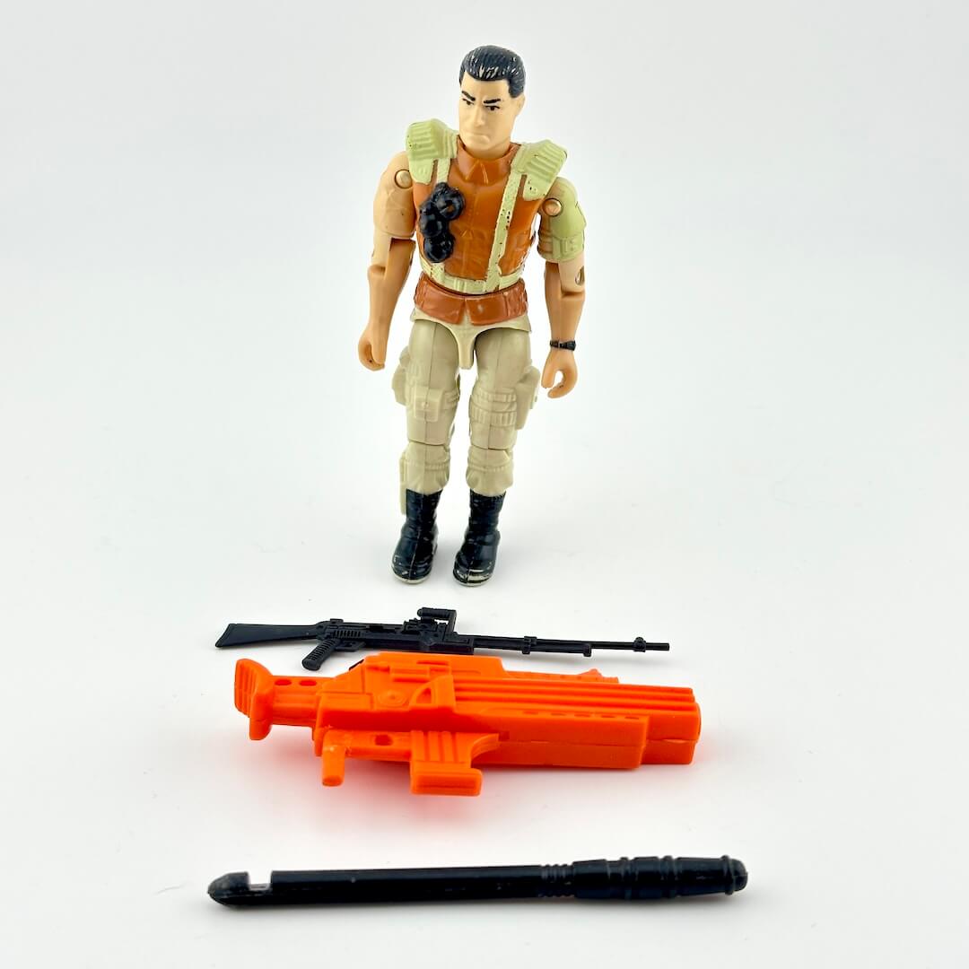 GI Joe action figure in beige and brown with black and orange accessories, photographed on white background. 