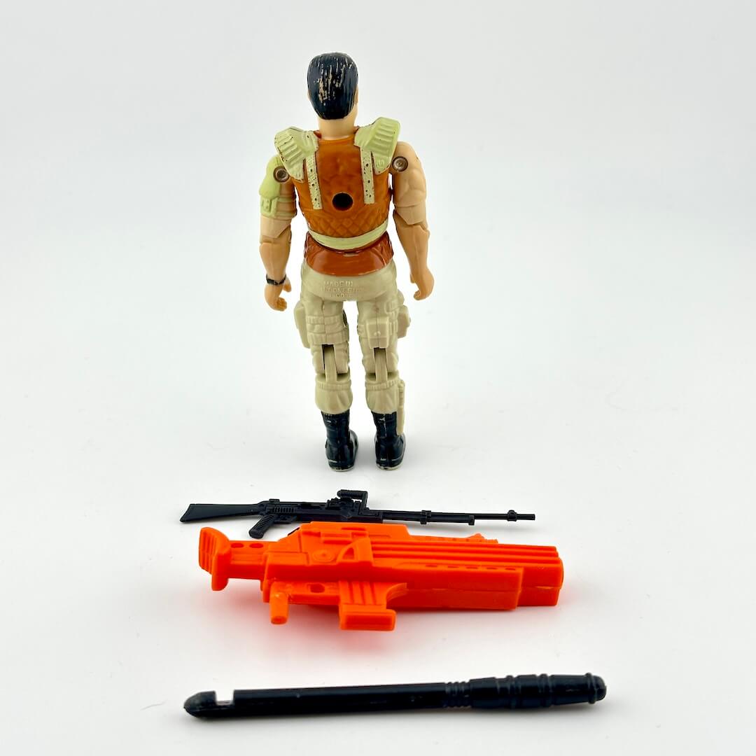 GI Joe action figure in beige and brown with black and orange accessories, photographed on white background. 