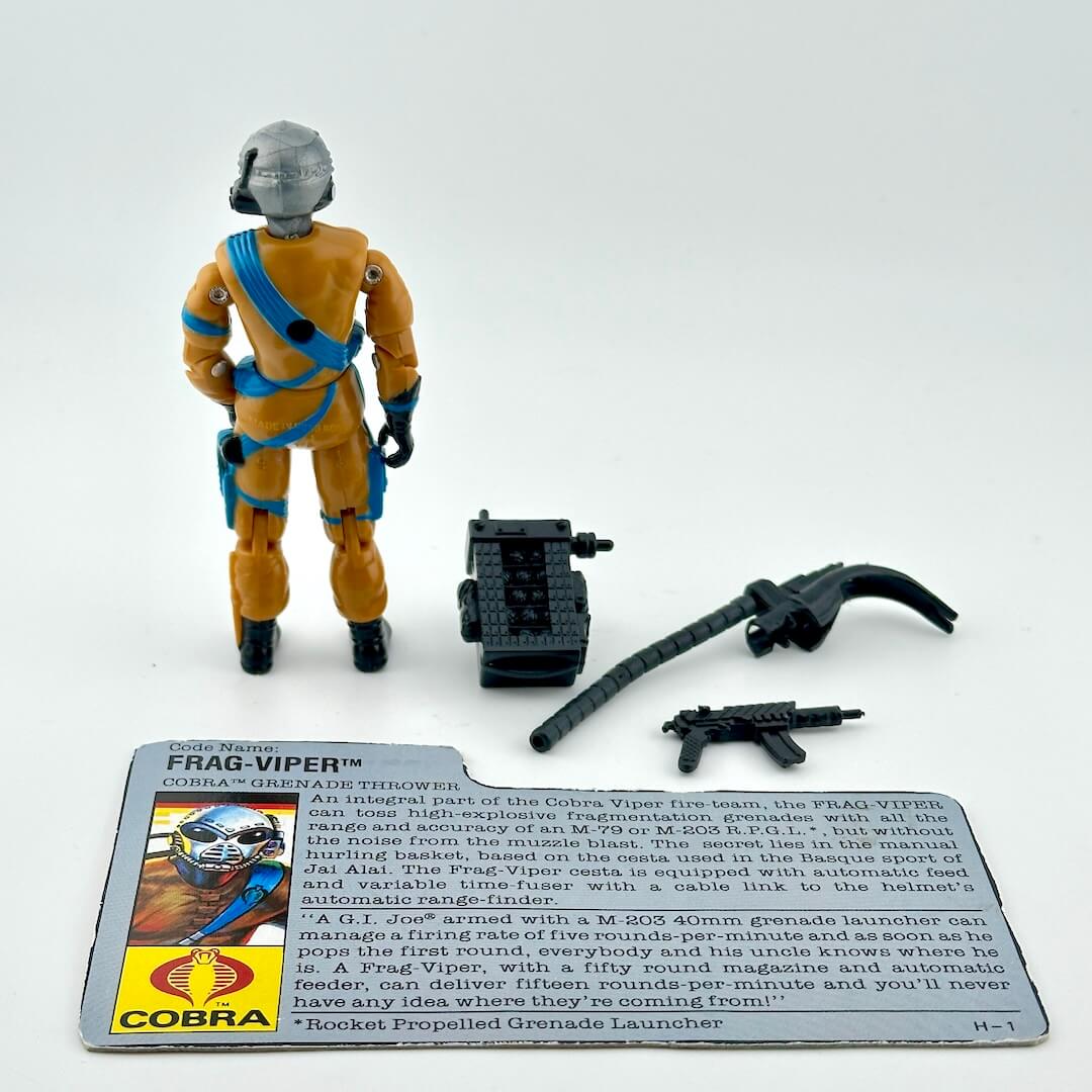 Toy figure in orange suit with accessories and card on a white background