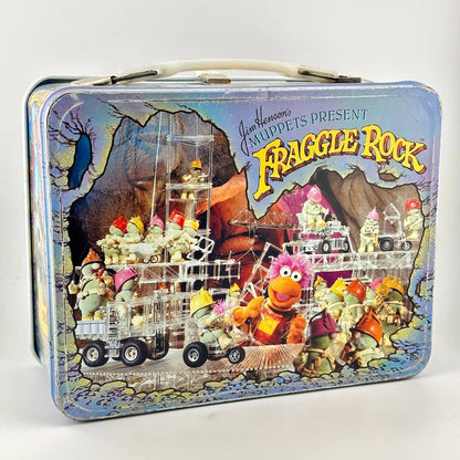 Vintage metal lunchbox with images from Fraggle Rock in color on side with wear along edges. 