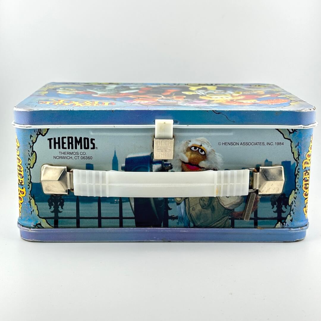 Top view of vintage metal lunchbox with white plastic latch and handle. 