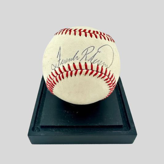 Signed Rawlings baseball with black ballpoint pen in sweet spot, resting on black base.
