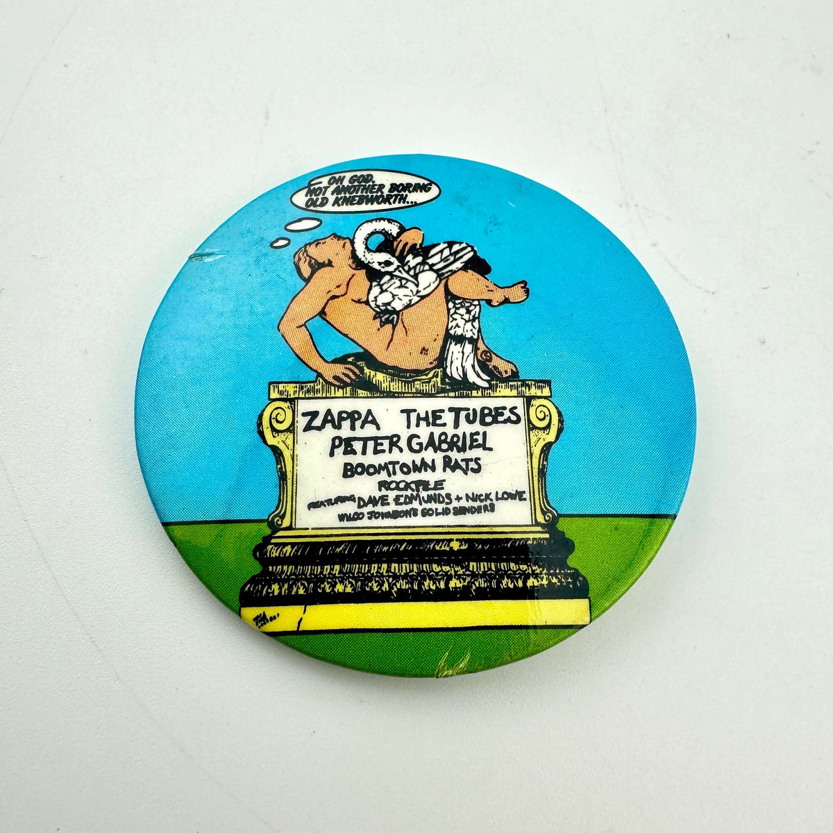 A circular pinback button badge featuring a comic-style illustration of man on a pedestal with the text below. 