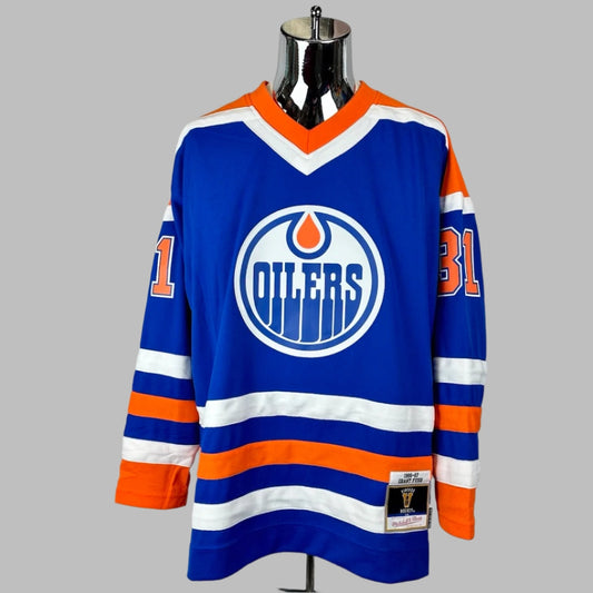 Jersey blue body & long sleeves, orange shoulders, white/orange stripes around waist & wrists. OILERS logo center chest.