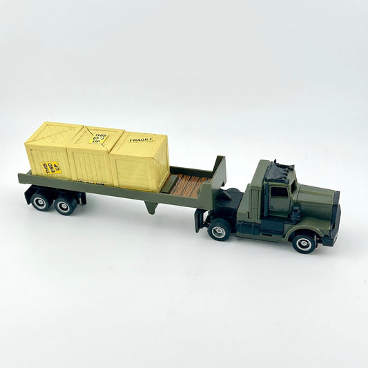 Model truck with a flatbed carrying a wooden crate on a white background