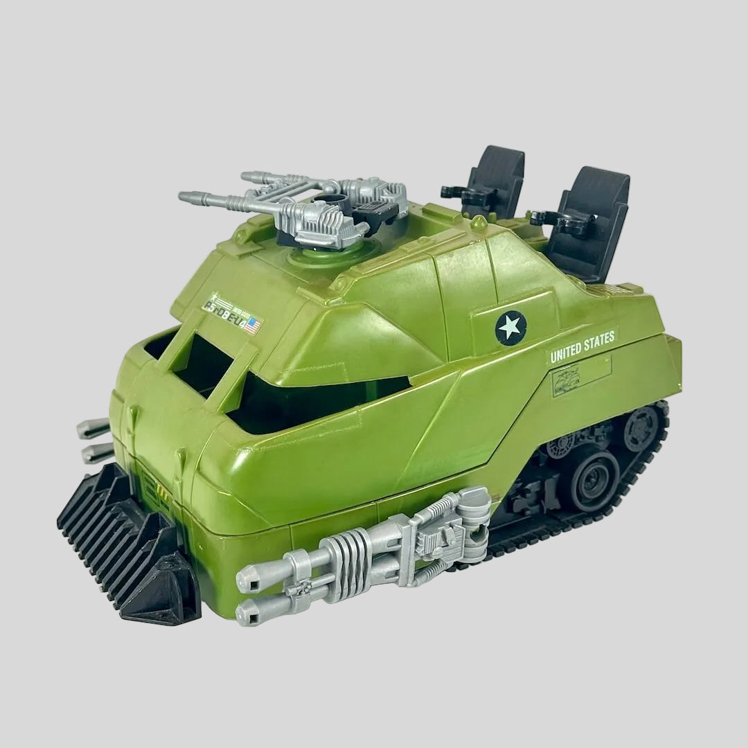 Green toy tank with silver and black accents on gray background. 