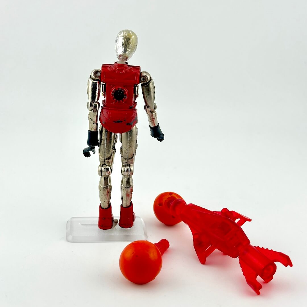 Silver and red humanoid action figure with red pack and orange missile accessory standing against white background. 
