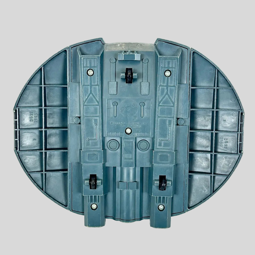 A toy spaceship accessory in dark gray-green with bright yellow stripes and a green hexagonal emblem.