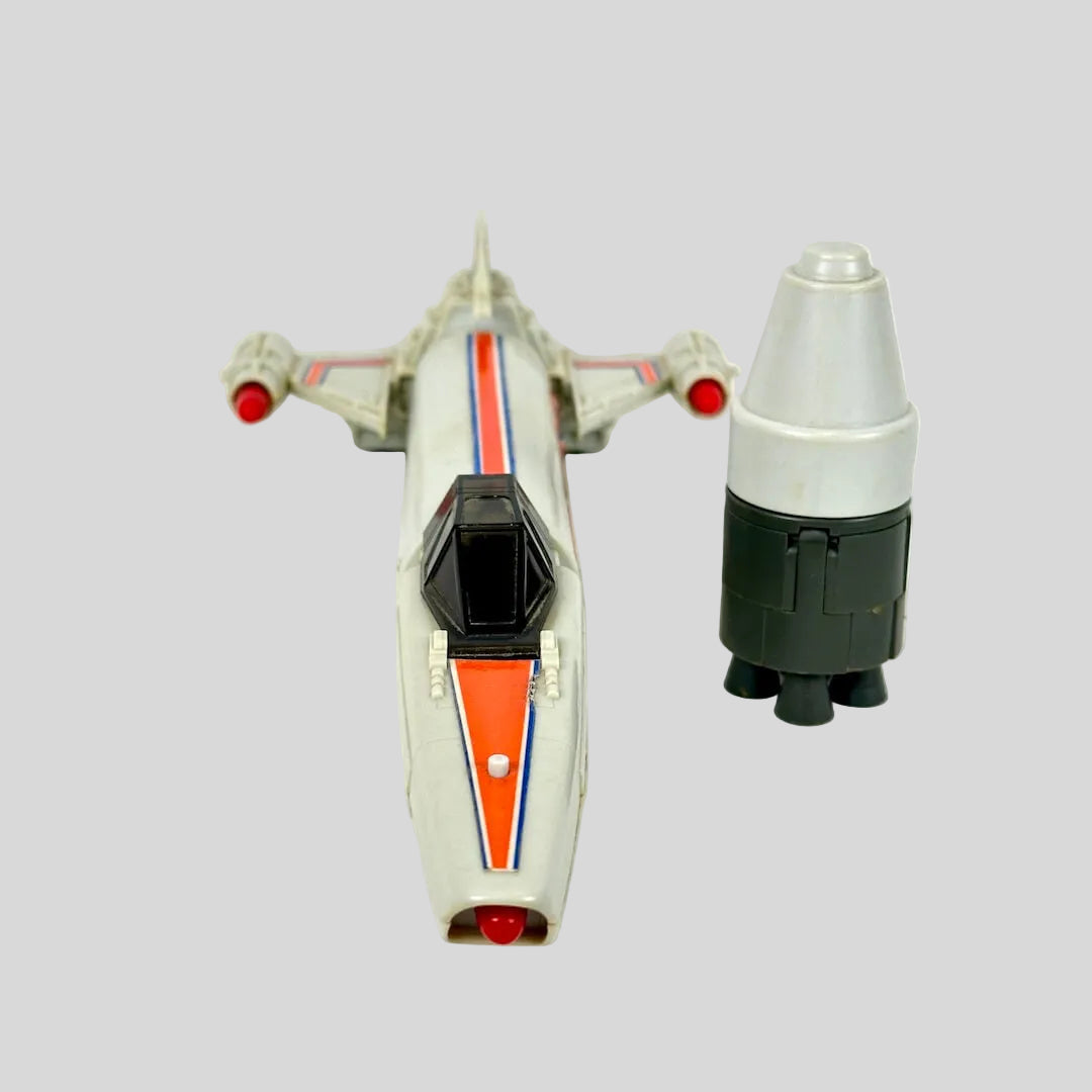 A vintage toy model of a sci-fi spaceship, shown alongside a matching cylindrical booster on a plain background.