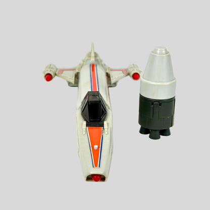 A vintage toy model of a sci-fi spaceship, shown alongside a matching cylindrical booster on a plain background.