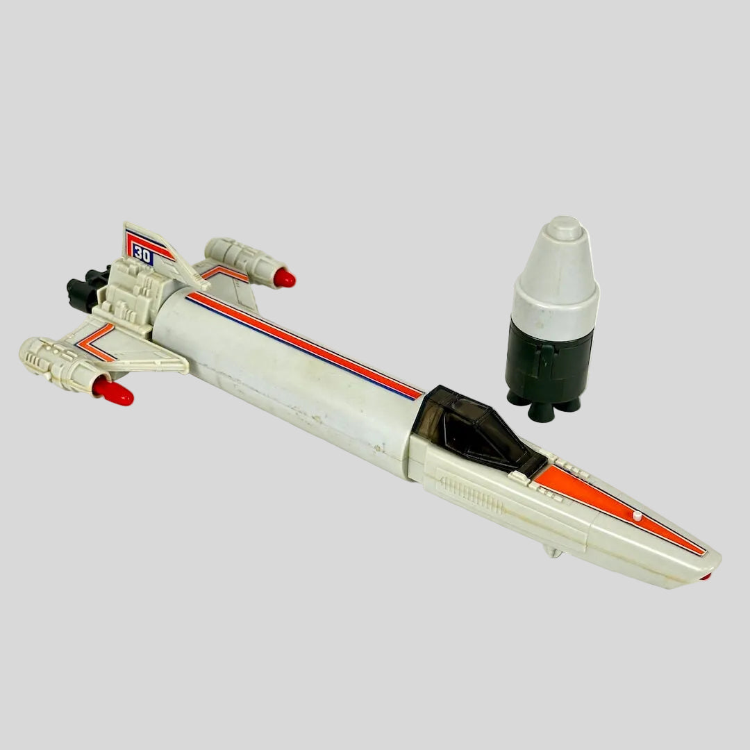Vintage toy spaceship with small satellite next to it on light surface. 