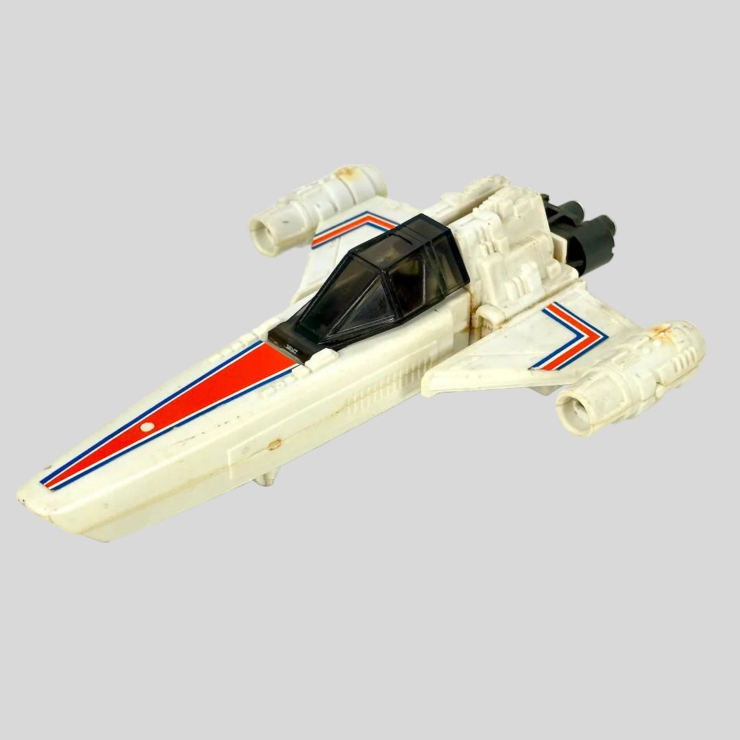 A vintage toy spacecraft in off-white plastic with orange and blue stripes.
