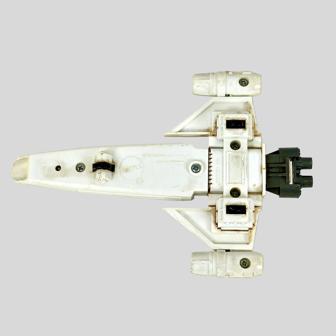 A vintage white plastic toy spaceship, shown from an underside view on a light gray background.