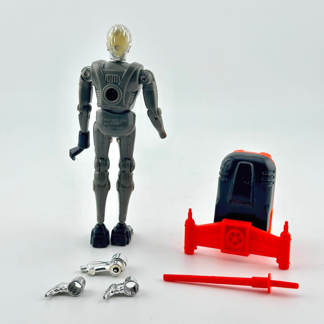 A toy silver robot standing next to a red vehicle accessory, with two silver weapon pieces and a red sword placed in front.