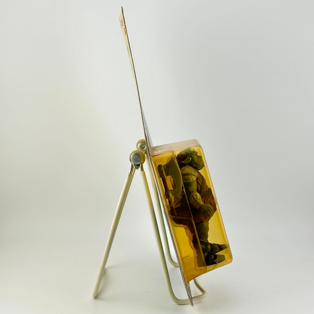 Side view of Star Wars action figure still in packaging on easel against white background. 