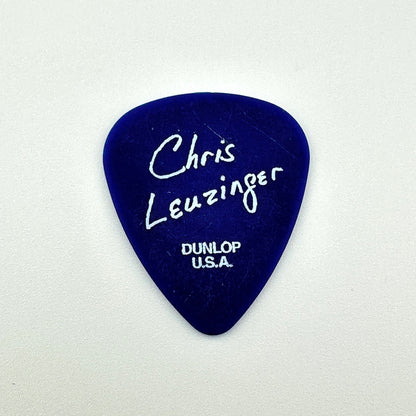 A dark blue guitar pick with white handwritten text reading 'Chris Leuzinger' and 'DUNLOP U.S.