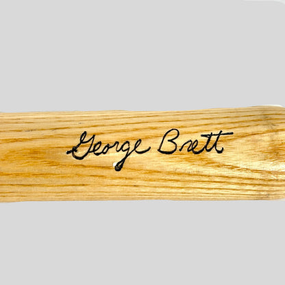 Wooden bat with 'George Brett' engraving on a light background
